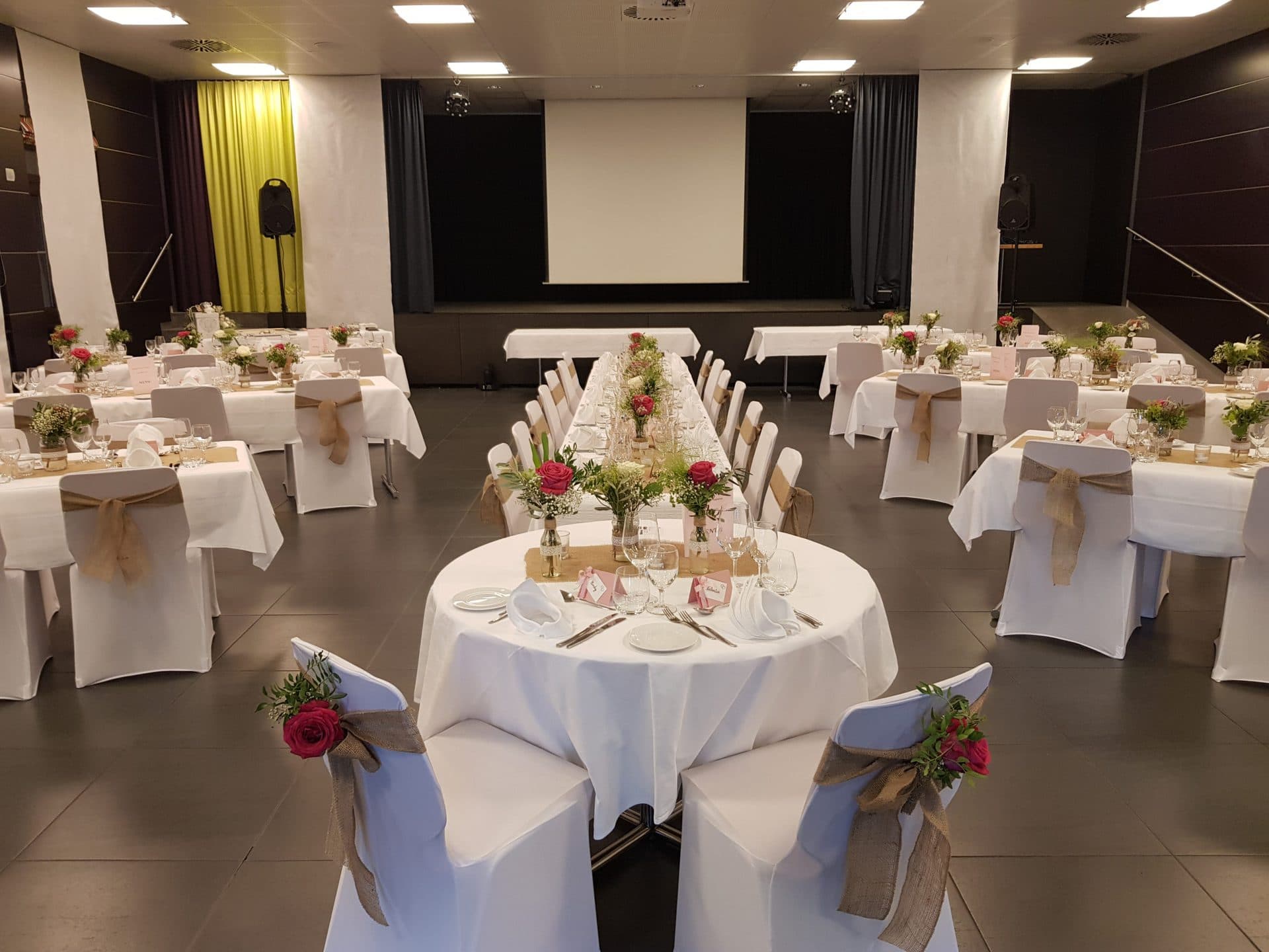 La grande salle dressée en banquet, écran de projection déployé