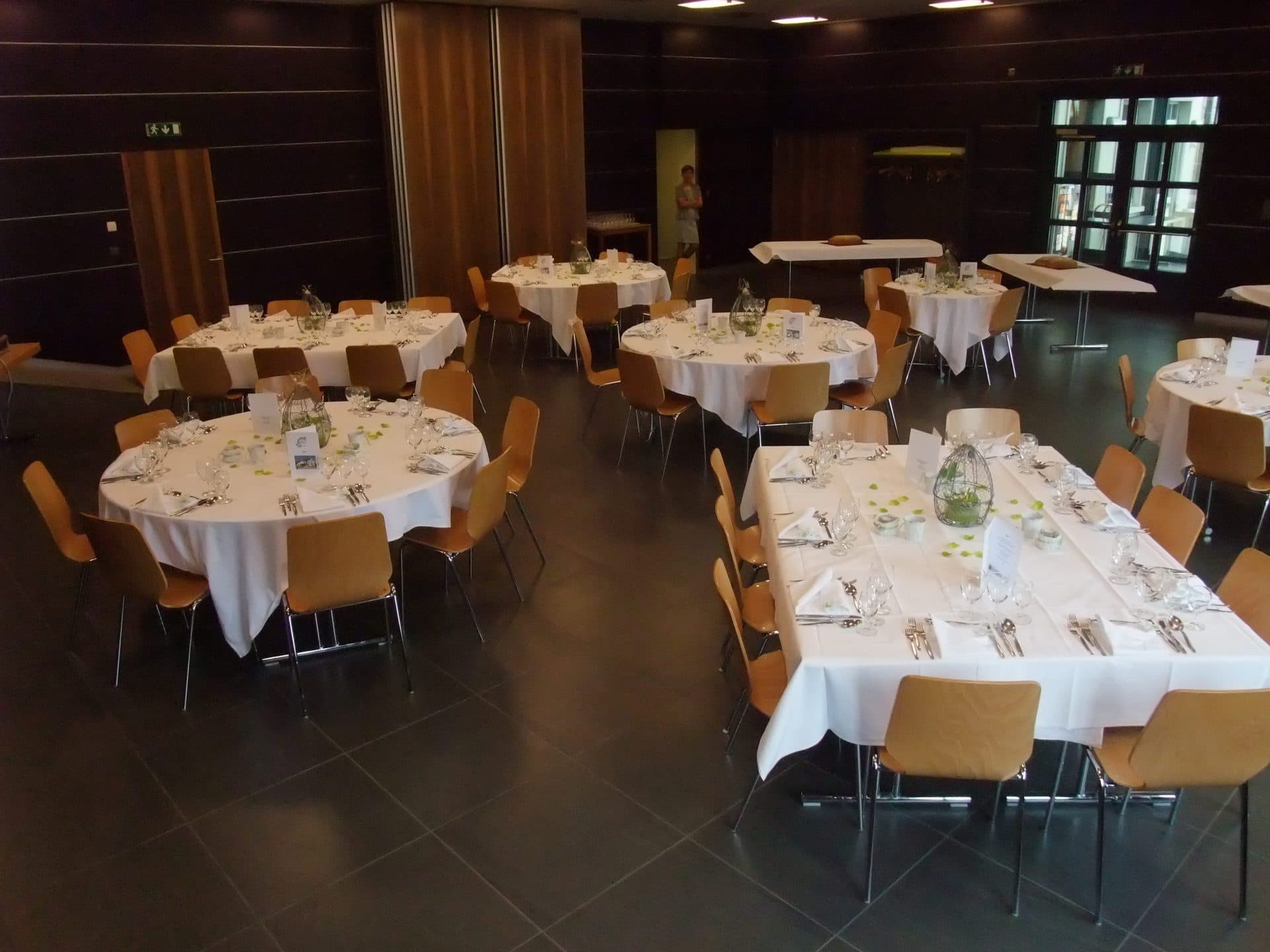 La grande salle de l'Auberge de la Croix-Verte dressée pour un banquet, boiseries et tables fleuries